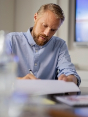 Mann sitzt an Arbeitsplatz über Dokumenten