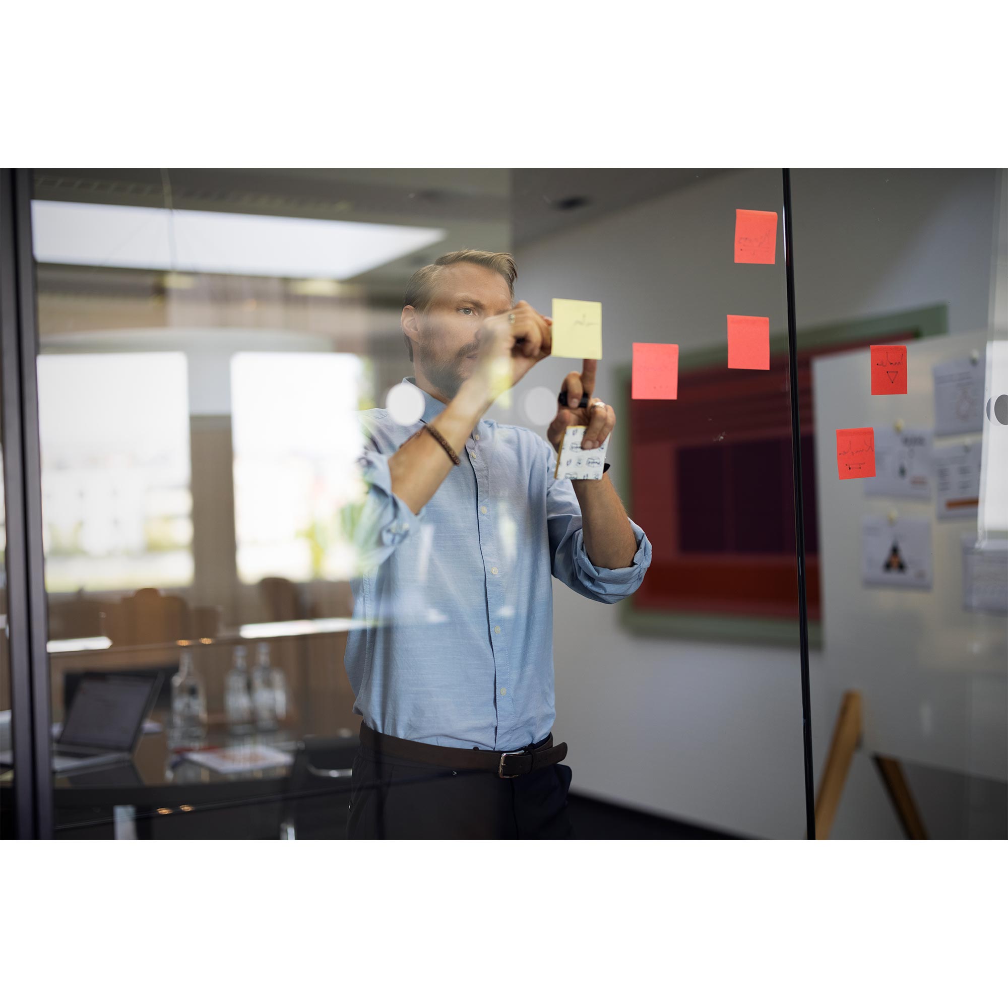Mann hinter Glasscheibe schreib auf Post-It