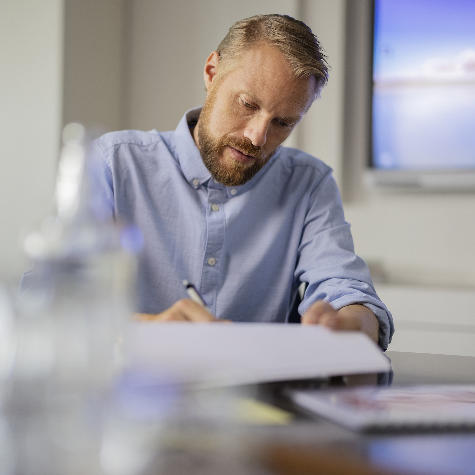 Mann sitzt an Arbeitsplatz über Dokumenten
