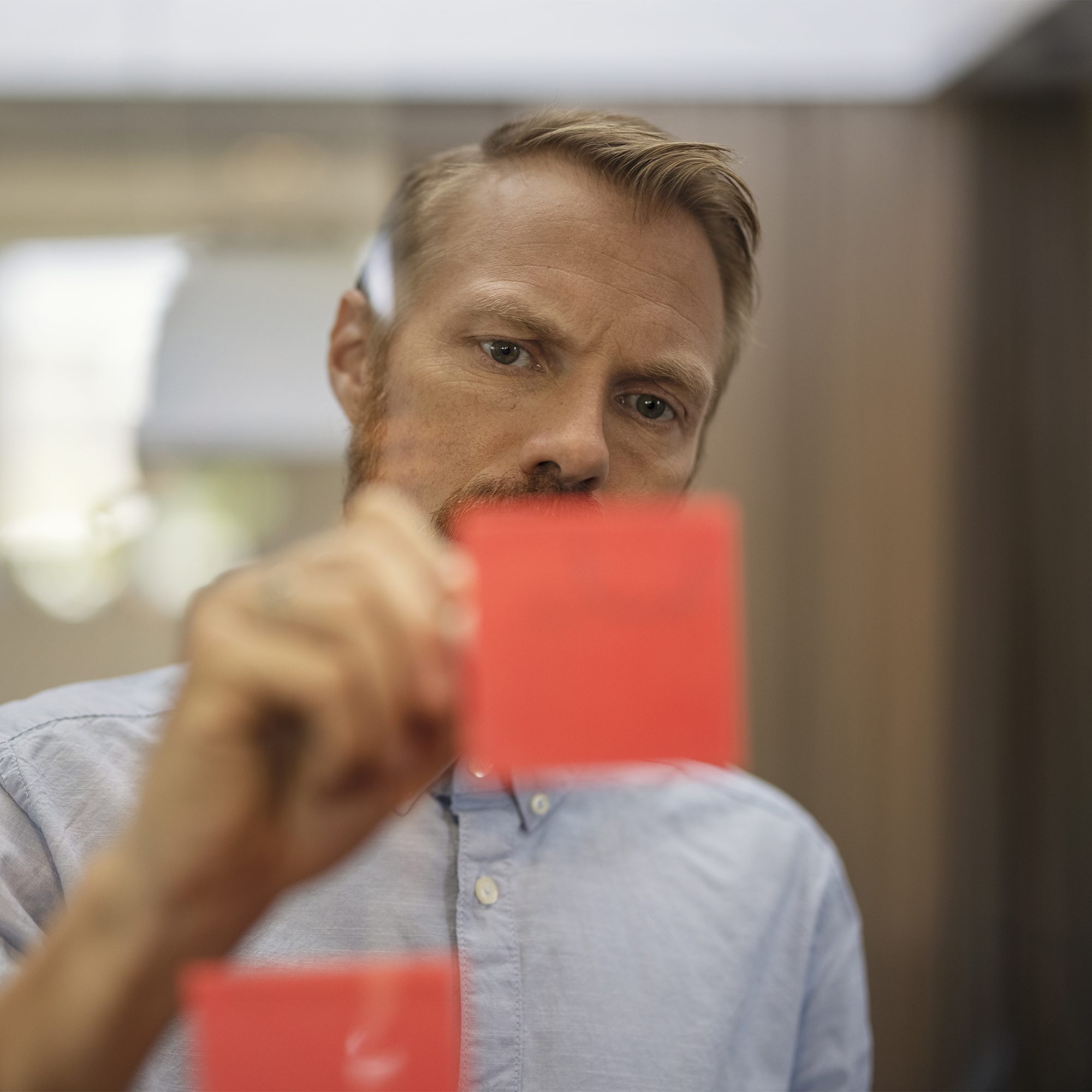 Mann schreibt auf Post-It-Zettel auf einer Glasscheibe