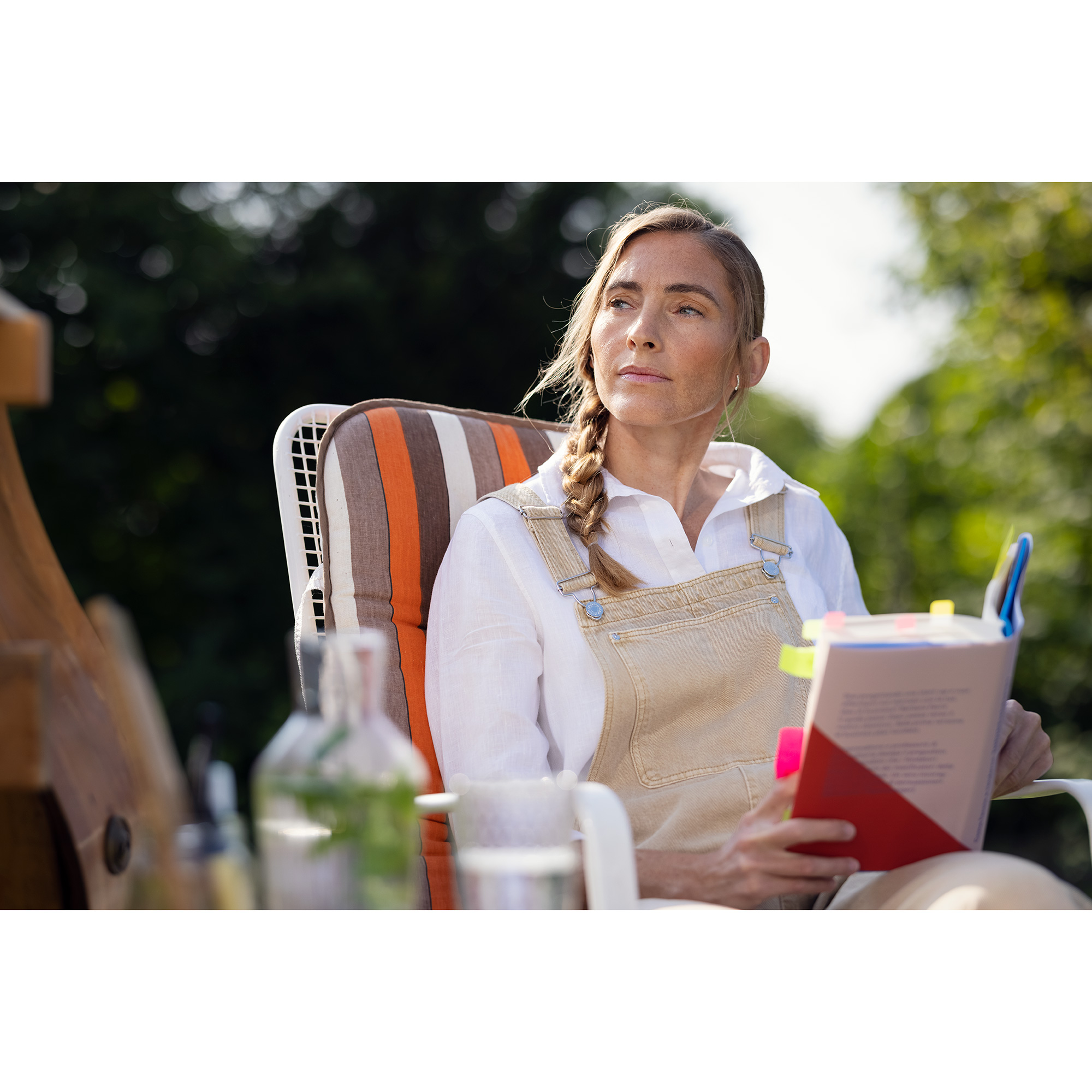 Frau sitzt im Garten mit Buch in der Hand
